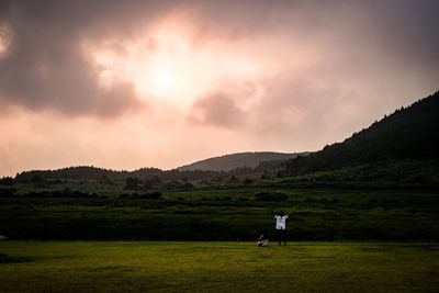 Man standing on field against sky during sunset