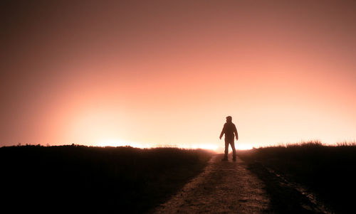 Full length of silhouette man standing on land against sky during sunset