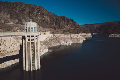 Hoover dam by colorado river against clear blue sky