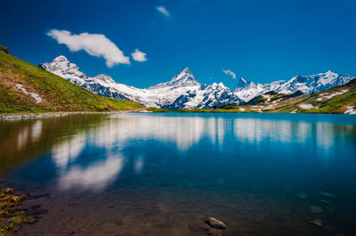 Scenic view of lake and snowcapped mountains against blue sky