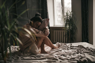 Young woman sitting on bed