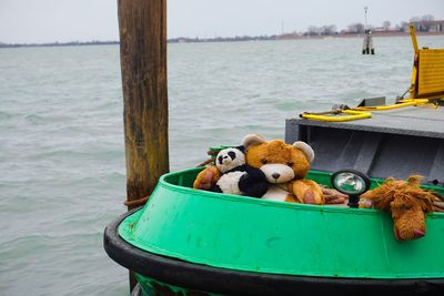 Stuffed toys in boat over sea against sky