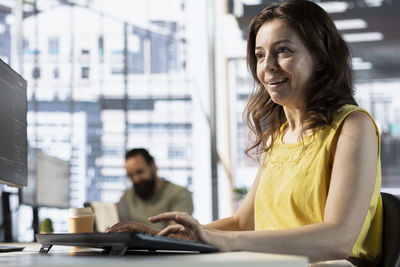 Young woman using laptop while sitting on table