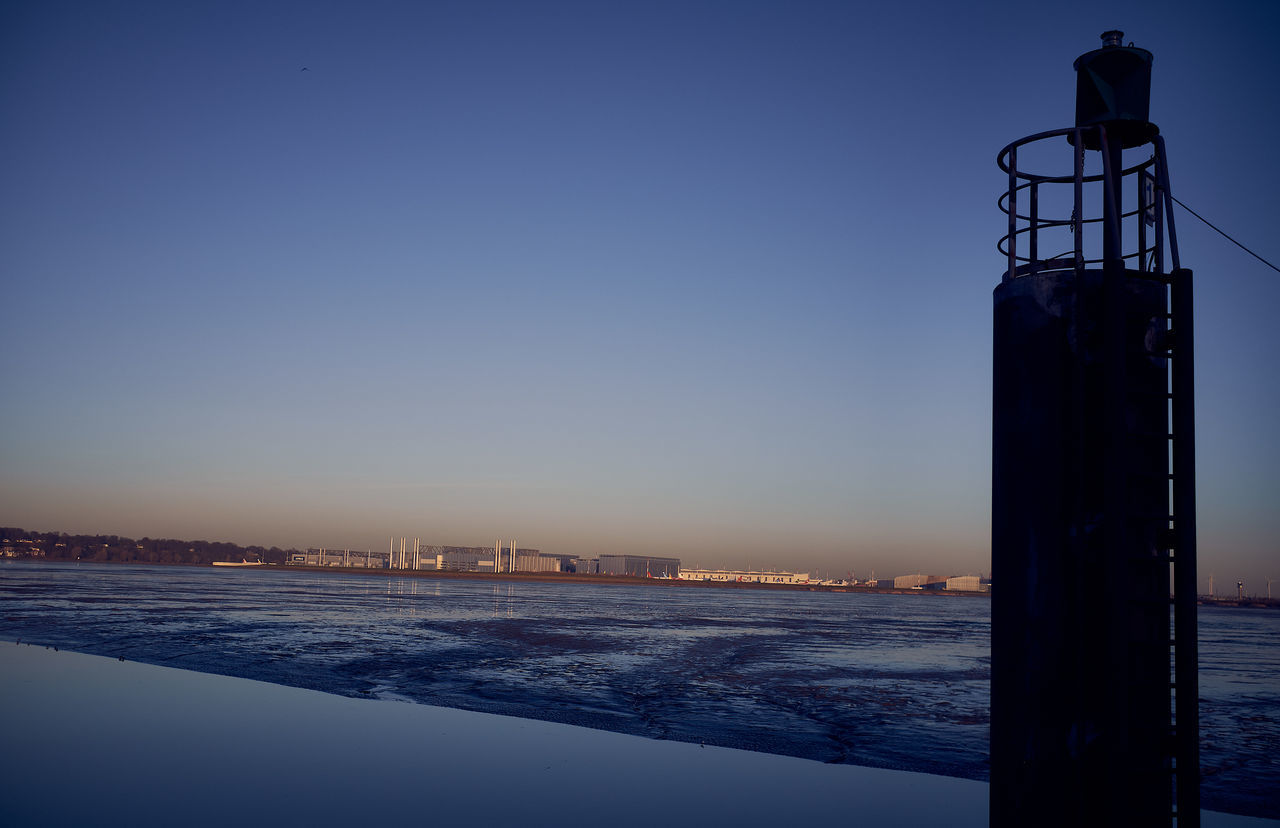 SEA BY CITY AGAINST CLEAR SKY AT DUSK