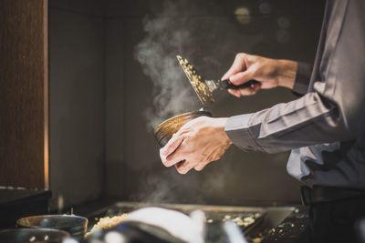 Midsection of man preparing food in kitchen