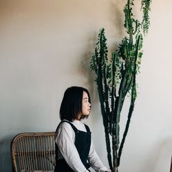 Woman looking away while sitting on seat at home