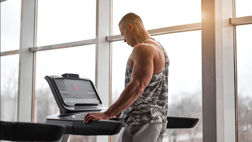 Side view of man standing on treadmill at gym