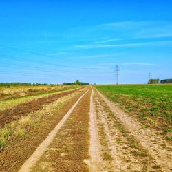 Road passing through agricultural field against sky