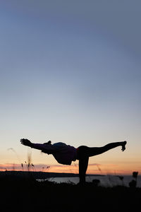 Silhouette woman with arms raised against sky during sunset