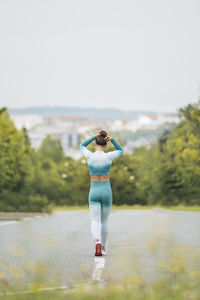 Sportswoman tying bun while walking on street