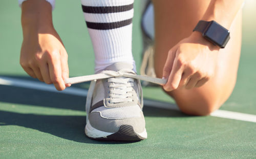 Low section of woman tying shoelace