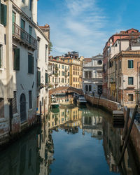 Canal by buildings against sky in venice, italy