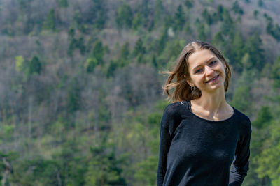 Young woman standing against trees