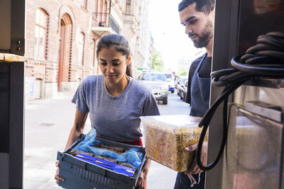 Young multi-ethnic owners carrying food at truck in city