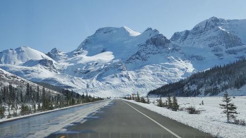 Road amidst snowcapped mountains against sky