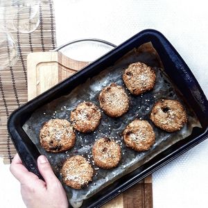 Cropped image of person holding fresh baked cookies in baking tray on table