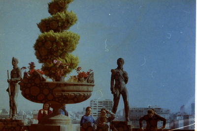 Group of people by sculpture against sky
