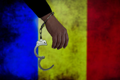 Cropped hand of male criminal with handcuffs against romanian flag