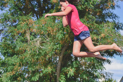 Low angle view of young woman against trees