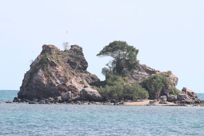 Rock formation in sea against clear sky