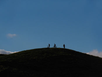 Silhouette of mountain bikers on top of hill