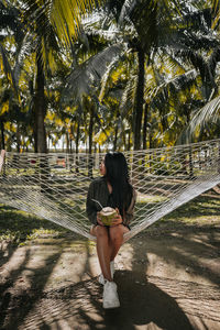 Woman sitting on palm tree