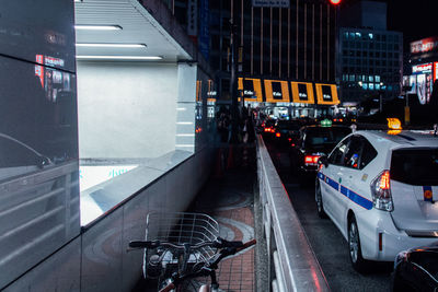 Cars on road by building at night in city