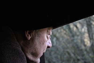 Side view of mature man looking through window in darkroom