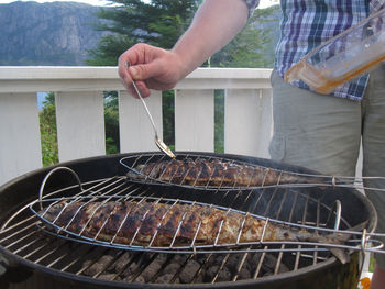 Close-up of person preparing food on barbecue grill