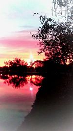 Silhouette trees by lake against sky during sunset