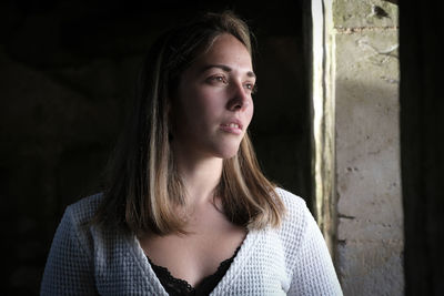 Portrait of young woman standing against wall