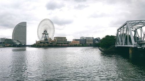 View of ferris wheel in city against cloudy sky