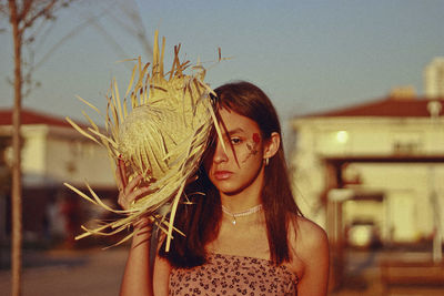 Portrait of teenage girl covering face with straw basket