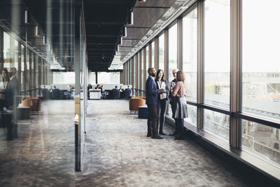 Business colleagues discussing while standing in office corridor