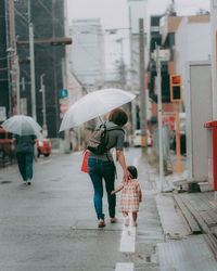 Full length of woman walking on wet street during rainy season