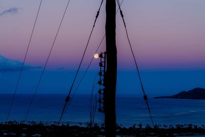 Silhouette of electricity pylon against sky during sunset