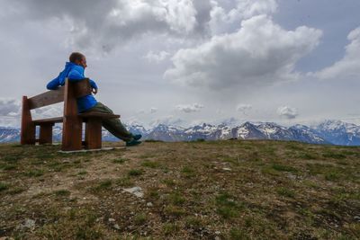 Full length of man sitting on bench at mountain
