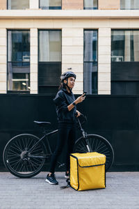 Delivery person using mobile phone by bicycle