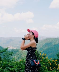 Woman wearing hat standing against mountains against sky