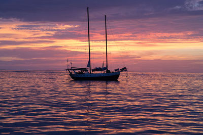 Sailboat sailing in sea at sunset