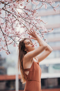 Fashion portrait of young woman in jumpsuit under the blossom tree