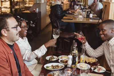 Cheerful male and female friends having wine in bar during party