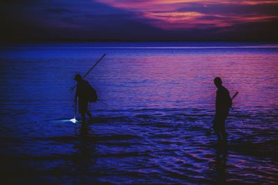 Rear view of silhouette man fishing in sea