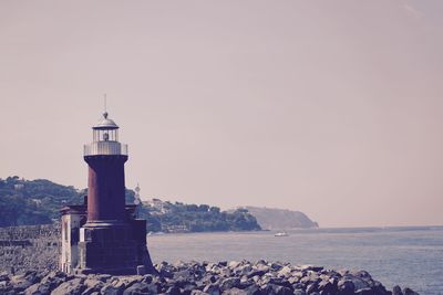 Lighthouse by sea against sky