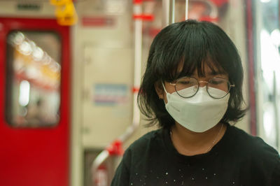 Close-up of young woman wearing eye glasses at commuter line public transportation