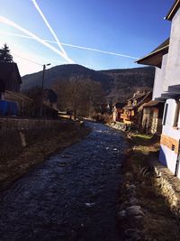 Road amidst houses and buildings against clear sky