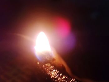 Close-up of burning candle against dark sky