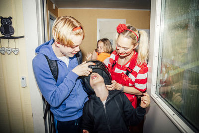 Brother and mother helping boy wear crash helmet