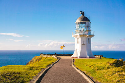 Lighthouse by sea against sky