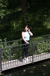 Woman standing on railing against trees